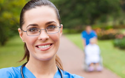 Caregiver posing with wheelchair in background